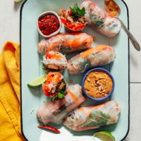 Tray of Crispy Shallot Spring Rolls with bowls of chili garlic and peanut sauces